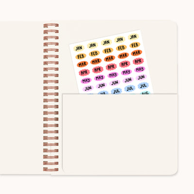 Colorful month labels on a planner with bronze spiral binding